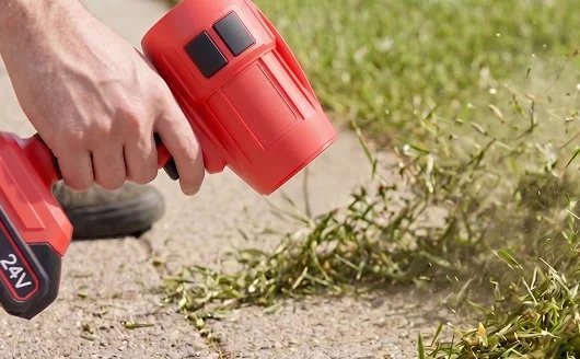 Wood Ranger blowing fresh grass clippings off a sidewalk edge, one-handed