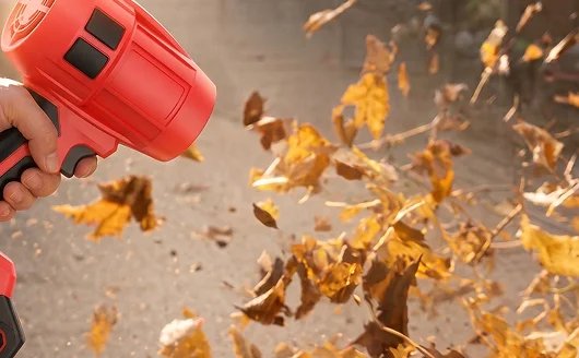 Wood Ranger Power Blower held in one hand, clearing dry leaves off a patio